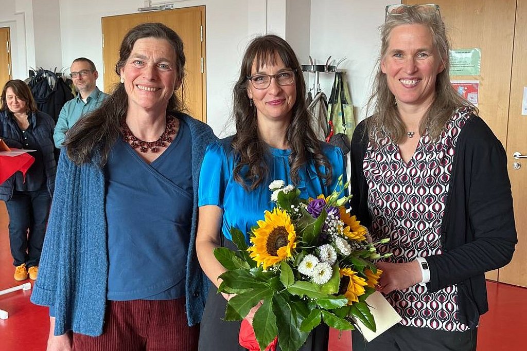 Gruppenfoto von Bettina Völter, Jana Einsporn und Gesine Bär. Die drei stehen nebeneinander im Audimax der ASH Berlin. Jana Einsporn hält einen Blumenstrauß in der Hand.