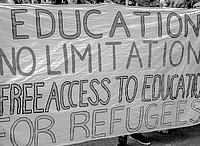 Several people hold a banner during a demonstration. It reads "Education no limitation, free access to education for refugees"