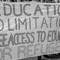 Several people hold a banner during a demonstration. It reads "Education no limitation, free access to education for refugees"