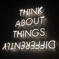 Think About Things Differently steht in Leuchtschrift auf schwarzem Hintergrund.