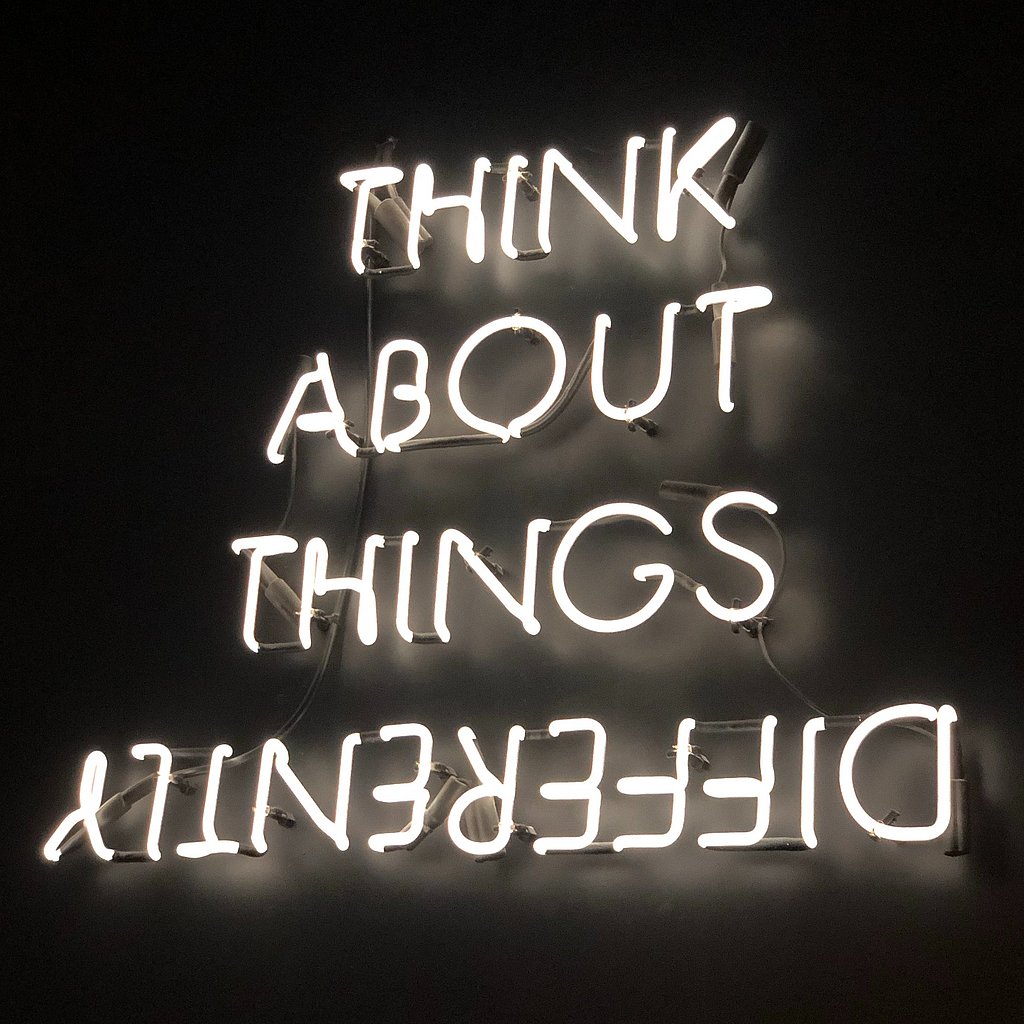 Think About Things Differently steht in Leuchtschrift auf schwarzem Hintergrund.