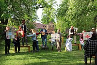 Auf dem Foto sind zahlreiche Menschen zu sehen, die inmitten eines Dorfes Theater spielen. 