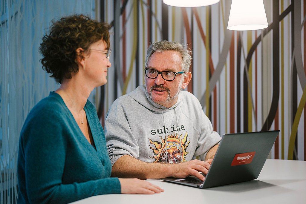 A woman and a man sit engrossed in a conversation in front of a laptop at ASH Berlin