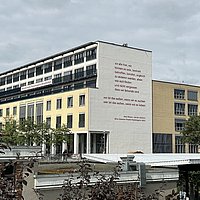 Maxi Obexers Gedicht an der Südfassade der ASH Berlin - davon der Bahnhof und Begrünung