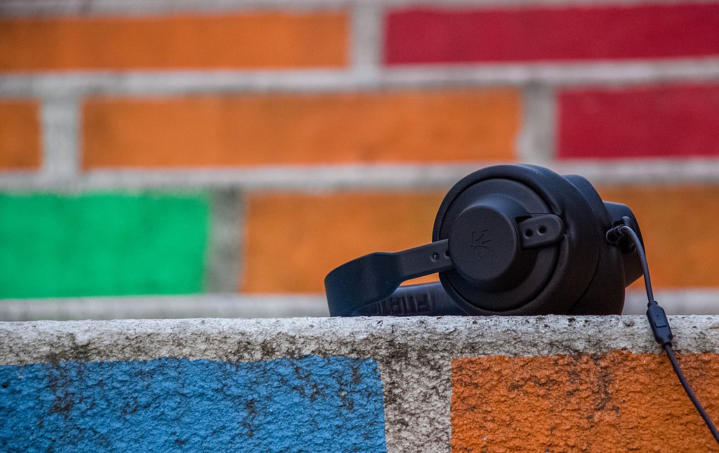 Schwarze Kopfhörer vor bunter Ziegelwand - Audio Hören Podcast