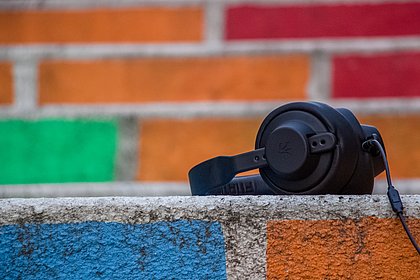 Schwarze Kopfhörer vor bunter Ziegelwand - Audio Hören Podcast