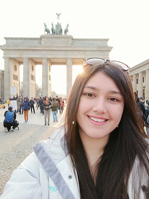 Paula in front of the Brandenburg Gate smiling directly at the camera: