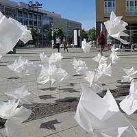 Auf dem Foto ist eine künstlerische Installation zu sehen. Auf dem Alice-Salomon-Platz wurden Blumen aus Papier installiert. 
