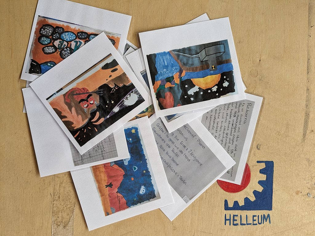 Auf einem Tisch liegen mehrere Zeichnungen von Planeten und kurze Steckbriefe von Planeten. In der unteren rechten Ecke ist das Helleum Logo gemalt.