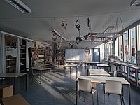 Blick in den Raum der WÄPT. Es sind Materialregale im Hintergrund und Gruppentische im raum verteilt erkennbar.