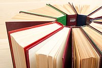 Blich von oben auf mehrere Bücher, die mit dem Rücken zueinander im Kreis aufgestellt sind.