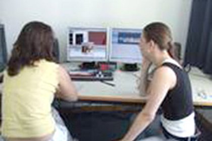 Zwei junge Frauen sitzen vor einem Rechner und schauen auf den Bildschirm