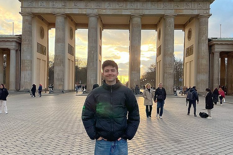 The photo shows the Spanish ERASMUS student Víctor del Amo Higueras in front of the Brandenburg Gate.