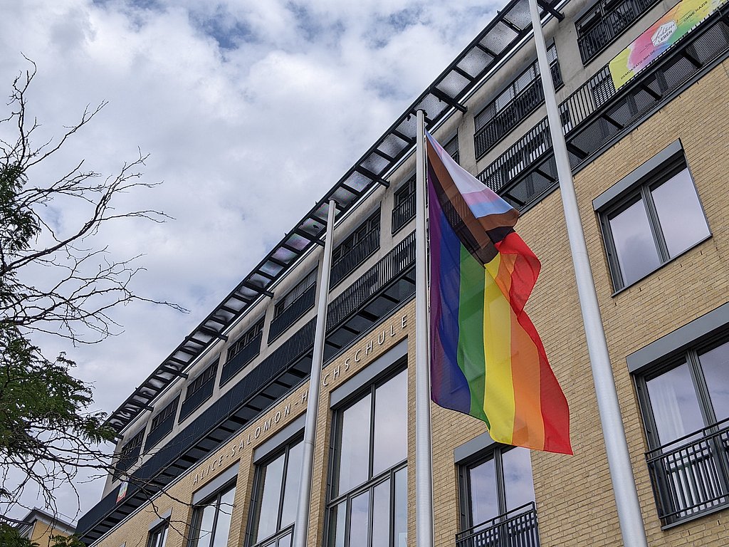 Auf dem Foto ist die Progressive Flag zu sehen, die vor der ASH Berlin an einem Fahnenmast weht. 