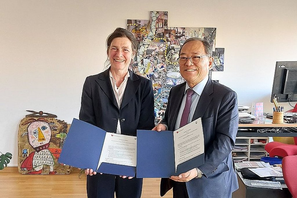 Auf dem Foto sind ASH-Präsidentin Bettina Völter und Shin-Il Yoon, Präsident der Kangnam University, zu sehen. Sie stehen nebeneinander im Büro der Präsidentin und halten gemeinsam den unterzeichneten Kooperationsvertrag in den Händen 