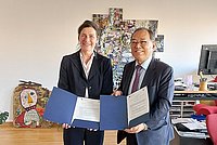Auf dem Foto sind ASH-Präsidentin Bettina Völter und Shin-Il Yoon, Präsident der Kangnam University, zu sehen. Sie stehen nebeneinander im Büro der Präsidentin und halten gemeinsam den unterzeichneten Kooperationsvertrag in den Händen 