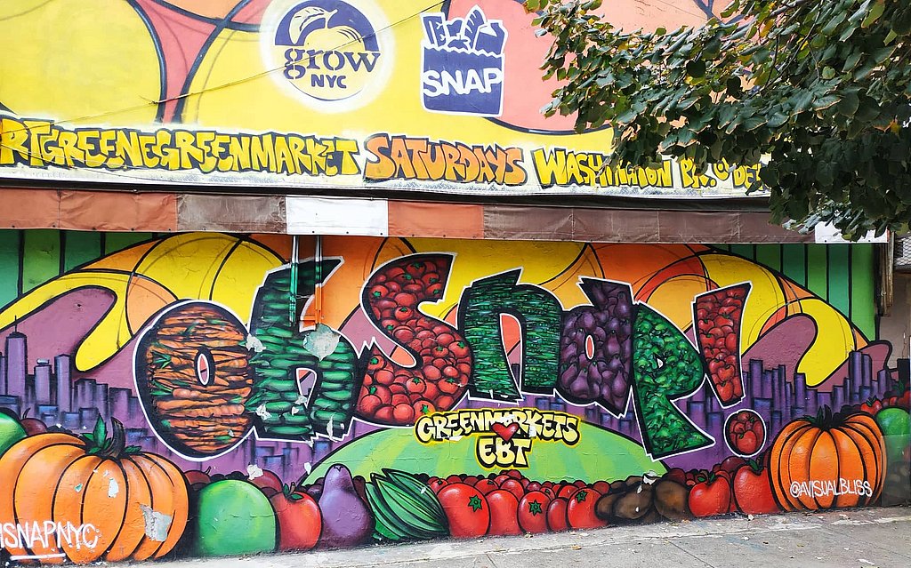 Eine mit Graffitti besprühte Wand wirbt für einen grünen Markt