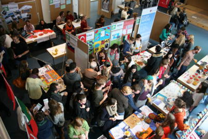 Ein stark besuchtes Audimax am International Day- Blick von oben auf die Stände der verschiedenen Partnerhochschulen der ASH Berlin.