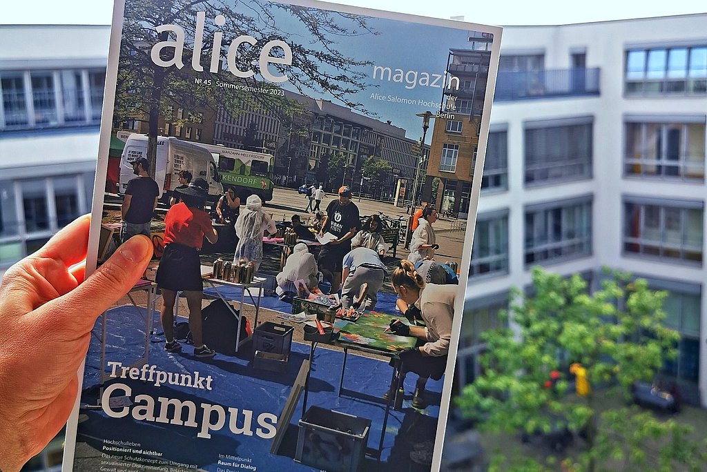 Eine Hand hält das Alice Magazin aus dem Fenster Richtung Innenhof im 3 Stock