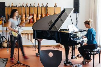 E-Gitarre, Schlagzeug und Flügel- eine Gruppe Studierender musiziert zusammen.