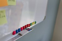 Man sieht ein Whitboard auf dem bunte Magneten sind