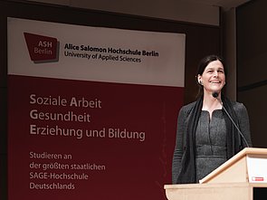 Rektorin Prof. Dr. Bettina Völter bei der Neujahrsbegrüßung an einem Pult, im Hintergrund eine ASH Stellwand