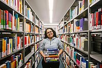 Eine Person mit Büchern in der Bibliothek.