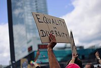 Eine Hand hält ein Schild hoch. Darauf steht: Equality in Diversity.