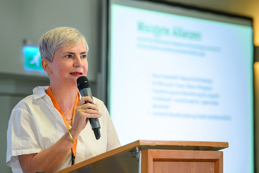 Esther Lehnert spricht auf einem Podium, Mikro in der Hand