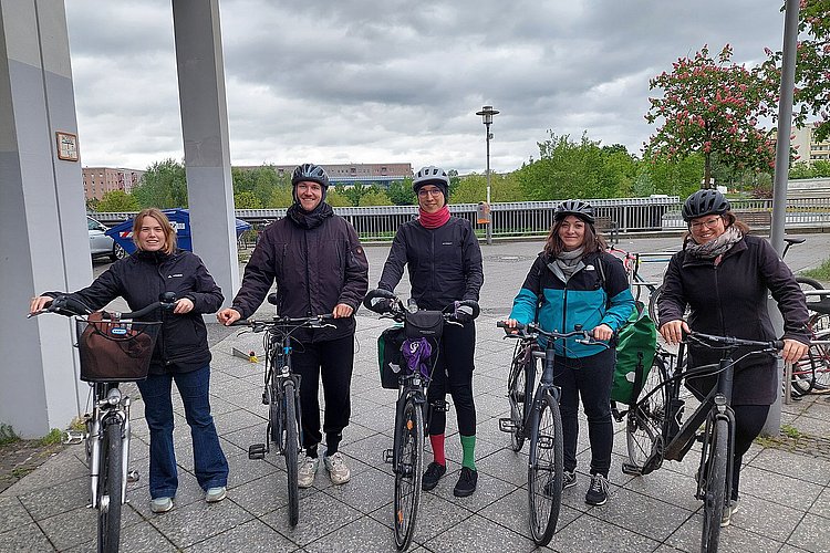 Foto von fünf Fahrradfahrenden vor dem Hauptgebäude der ASH Berlin